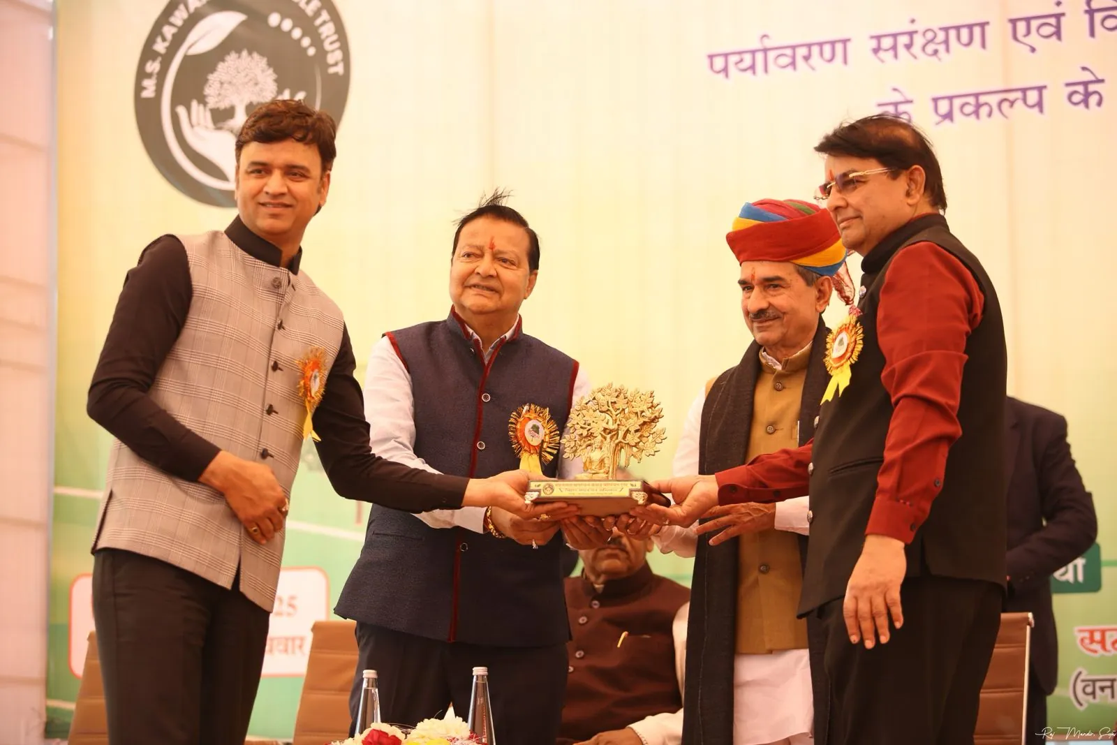 Felicitation on stage at the Pali Oxygen Park event, in front of the partner trust's banner