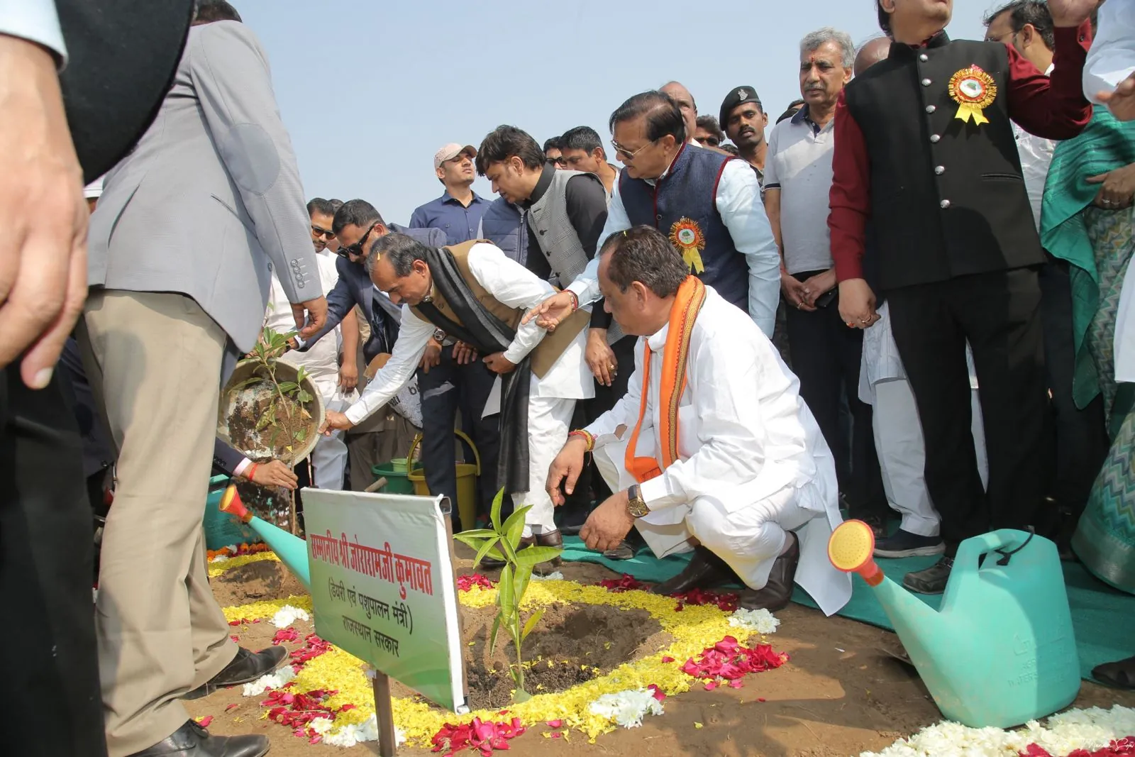 A guest kneels to plant a sapling beside a flower-decorated pit at Pali Oxygen Park